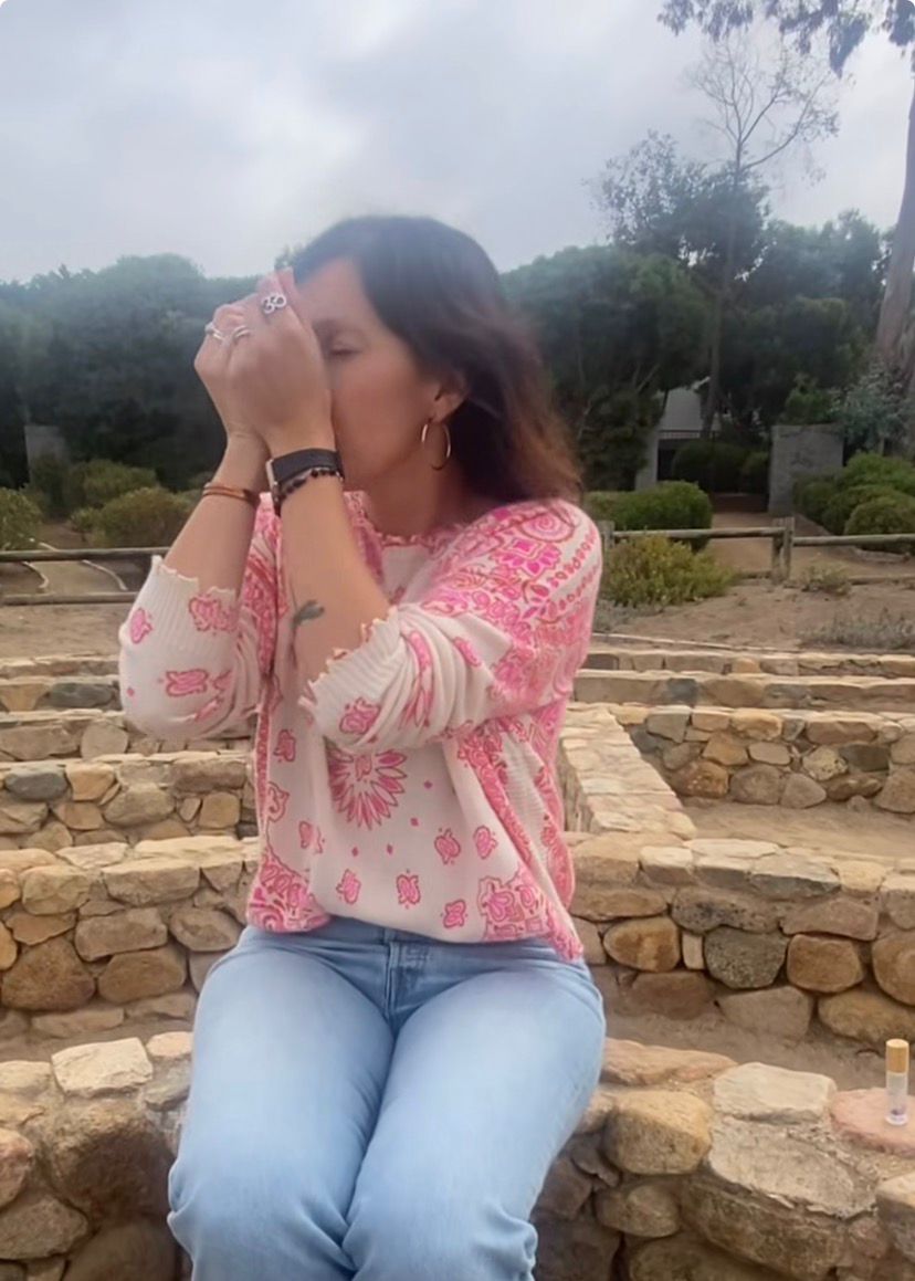 Mujer sentada en el laberinto oliendo una composición aromática